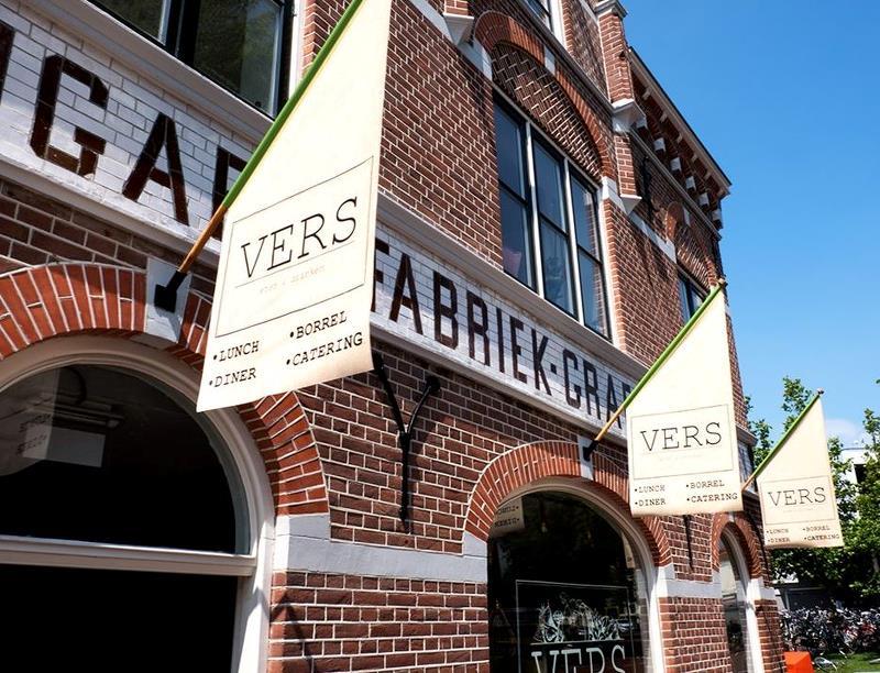 Buitenaanzicht Vers in Alkmaar met vlaggen met het logo van Vers